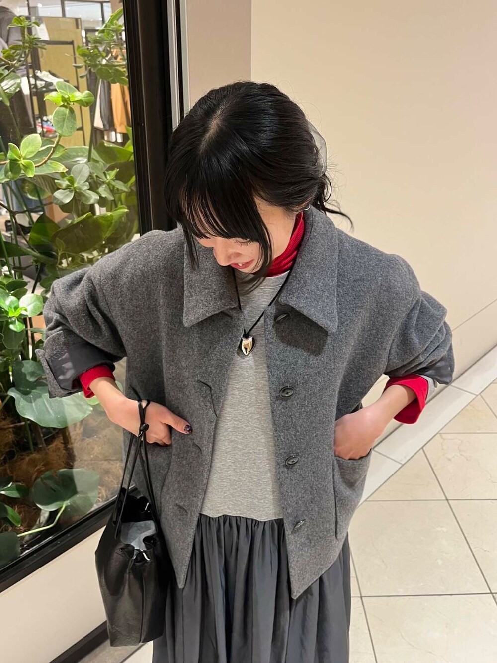 ブラック系のショルダーバッグ、レッド系のTシャツ/カットソー、ブラック系のブーツを着用したレディースの秋コーディネートの5枚目の写真