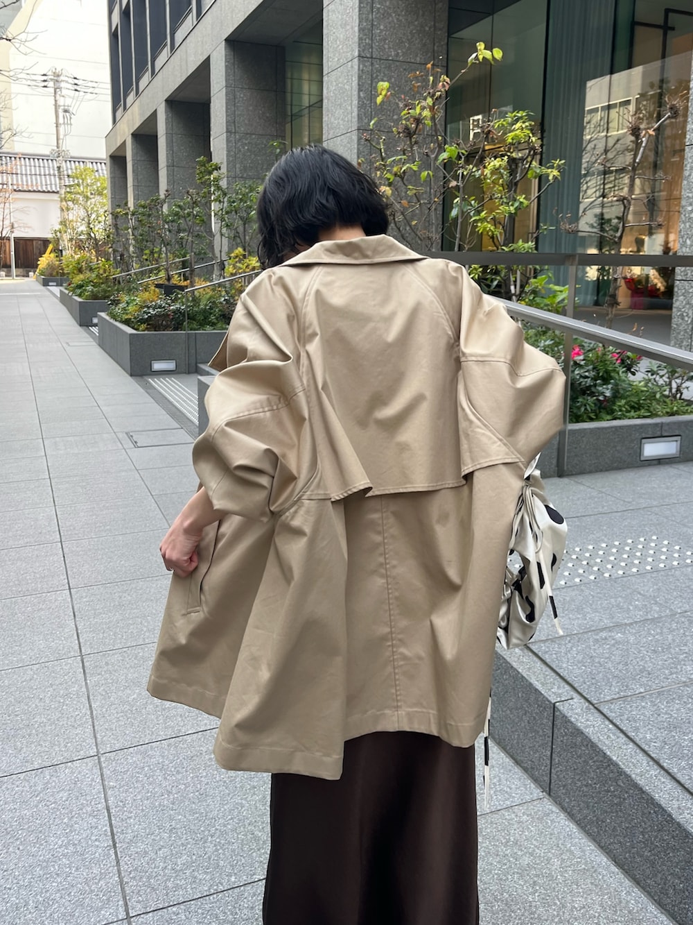 ホワイト系のキャミソール、ベージュ系のトレンチコート、ホワイト系のTシャツ/カットソーを着用したレディースの冬コーディネートの7枚目の写真