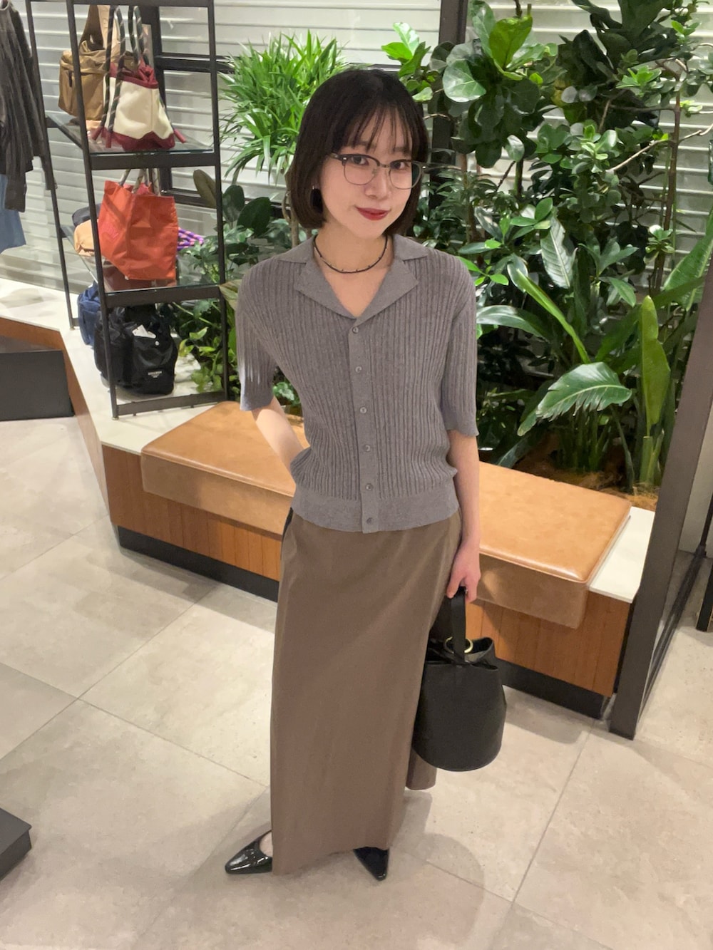 グレー系のニット/セーター、グレー系のスカート、ブラック系のハンドバッグを着用したレディースの春コーディネートの5枚目の写真