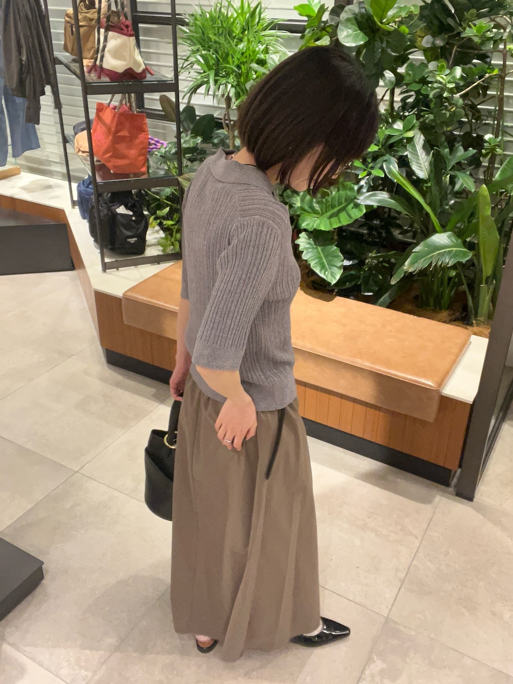 グレー系のニット/セーター、グレー系のスカート、ブラック系のハンドバッグを着用したレディースの春コーディネートの3枚目の写真