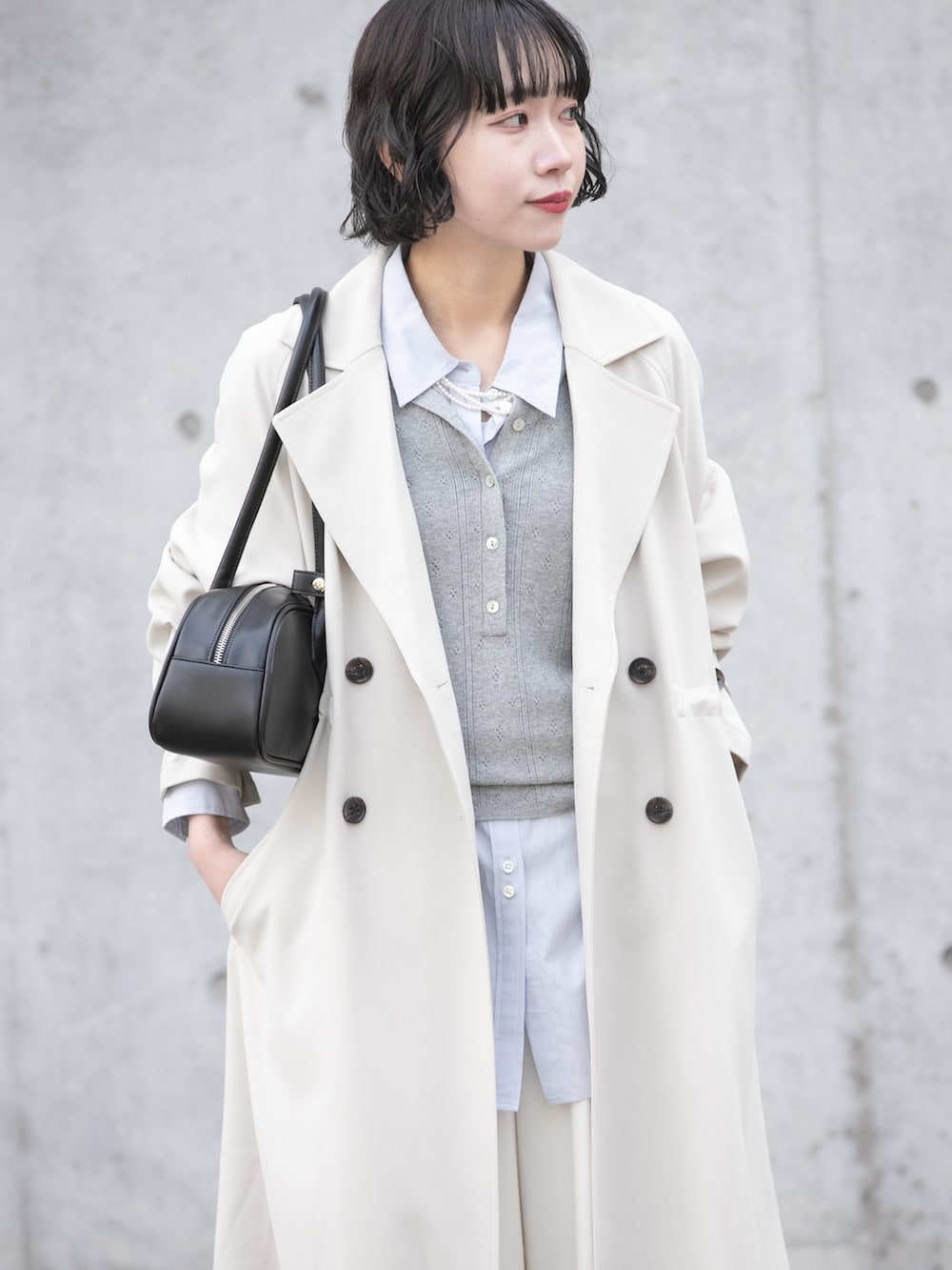 グレー系のトレンチコート、グレー系のニット/セーター、ブルー系のシャツ/ブラウスを着用したレディースの冬コーディネートの7枚目の写真
