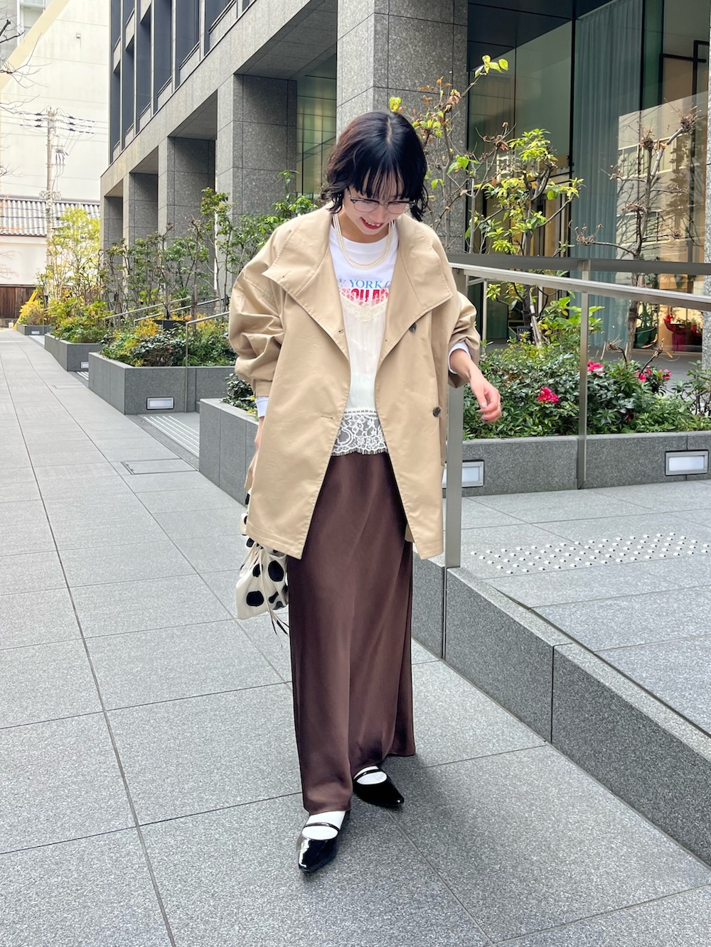 ホワイト系のキャミソール、ベージュ系のトレンチコート、ホワイト系のTシャツ/カットソーを着用したレディースの冬コーディネートの3枚目の写真