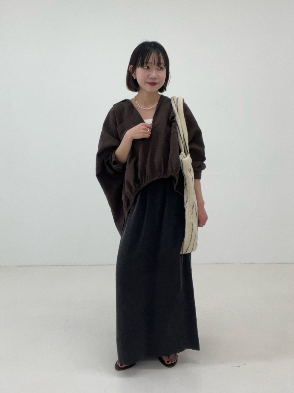 ブラウン系のシャツ/ブラウス、グレー系のスカート、ホワイト系のトートバッグを着用したレディースの春コーディネートの4枚目の写真