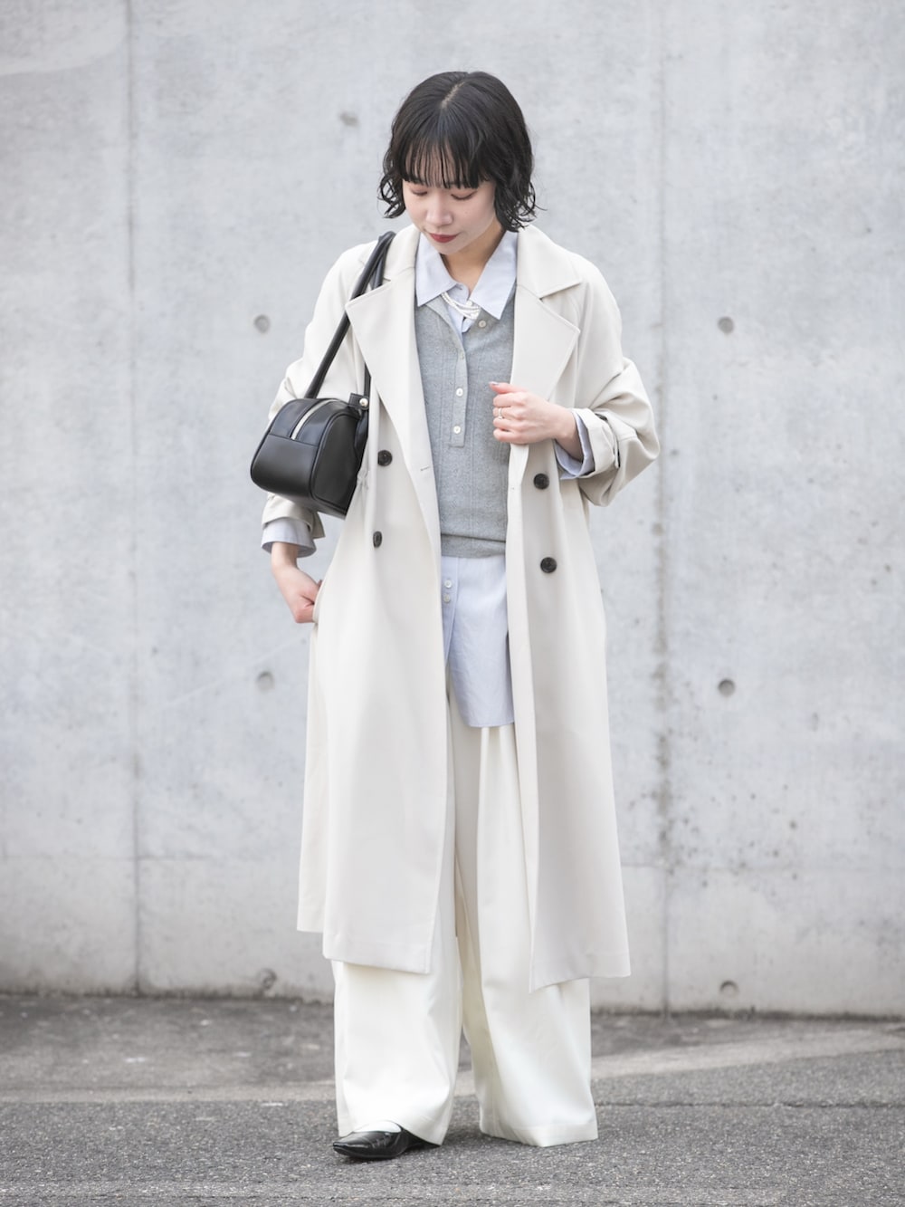 グレー系のトレンチコート、グレー系のニット/セーター、ブルー系のシャツ/ブラウスを着用したレディースの冬コーディネートの2枚目の写真