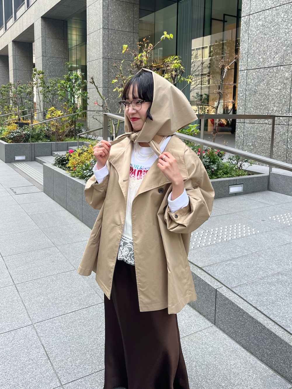 ホワイト系のキャミソール、ベージュ系のトレンチコート、ホワイト系のTシャツ/カットソーを着用したレディースの冬コーディネートの8枚目の写真