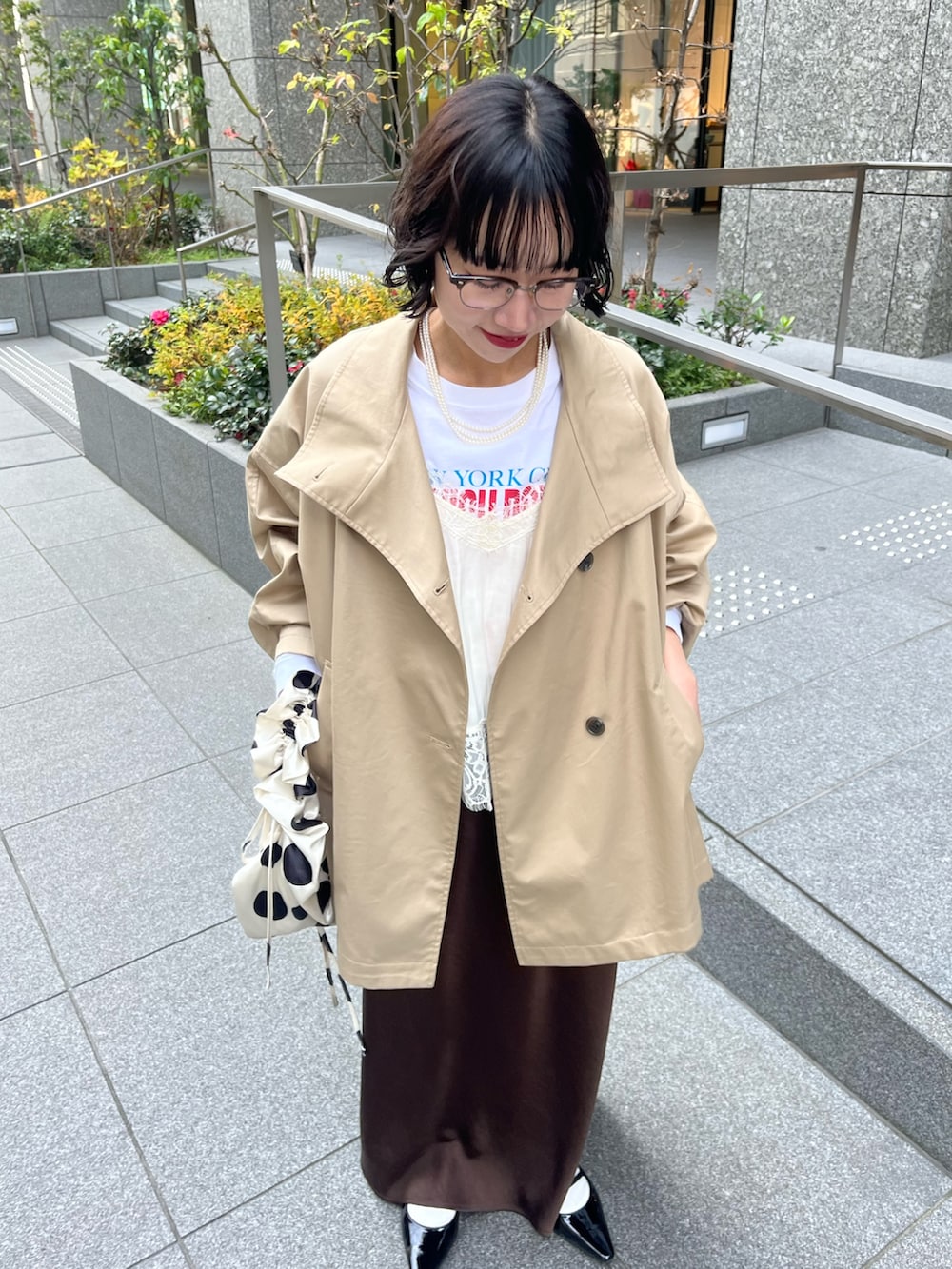 ホワイト系のキャミソール、ベージュ系のトレンチコート、ホワイト系のTシャツ/カットソーを着用したレディースの冬コーディネートの4枚目の写真