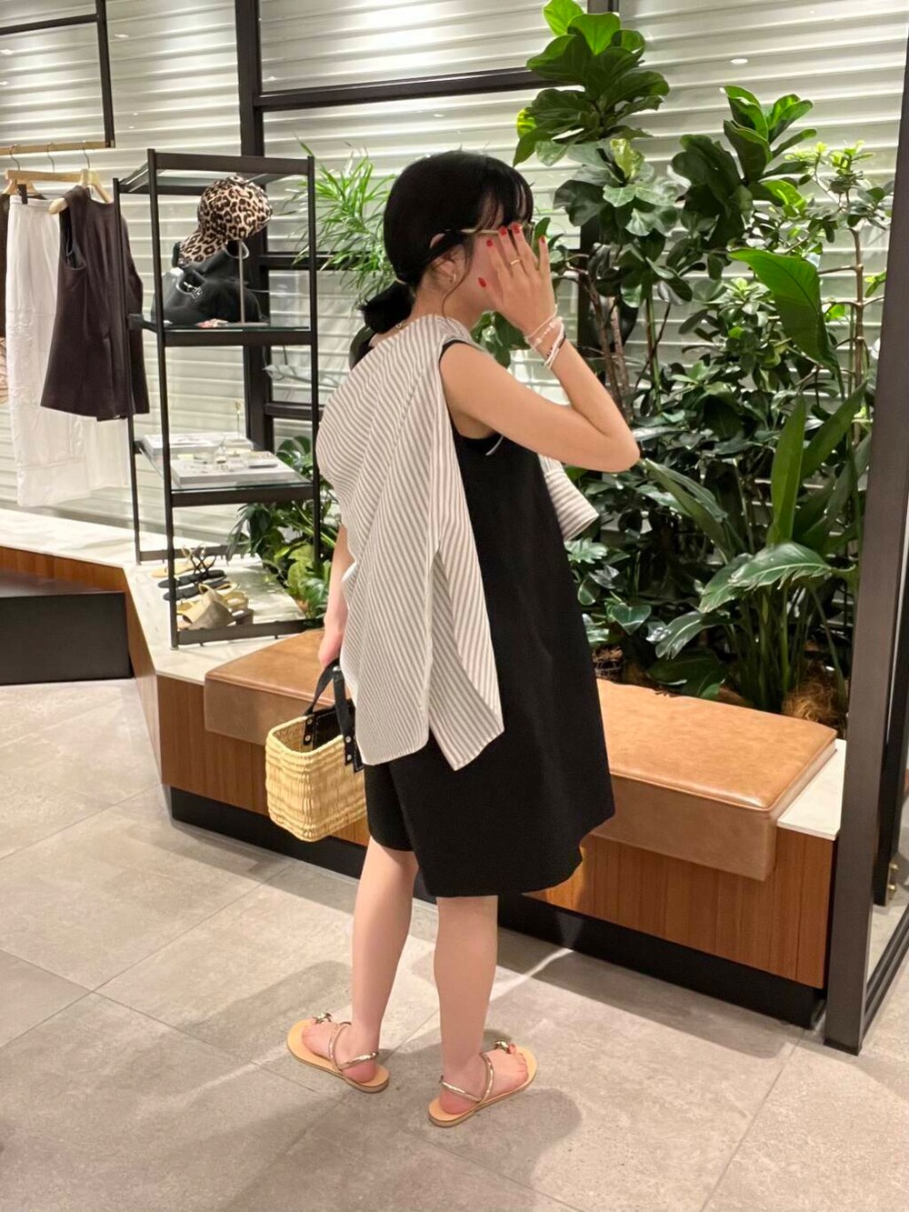 ブラック系のかごバッグ、ブラック系のシャツ/ブラウス、ゴールド系のサンダルを着用したレディースの夏コーディネートの2枚目の写真