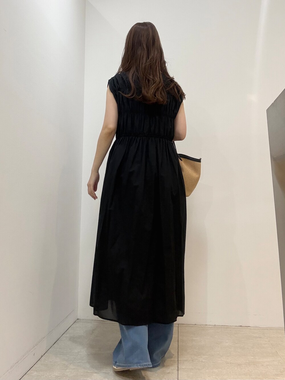ブルー系のデニムパンツ、ベージュ系のトートバッグ、ホワイト系のサンダルを着用したレディースの春コーディネートの2枚目の写真