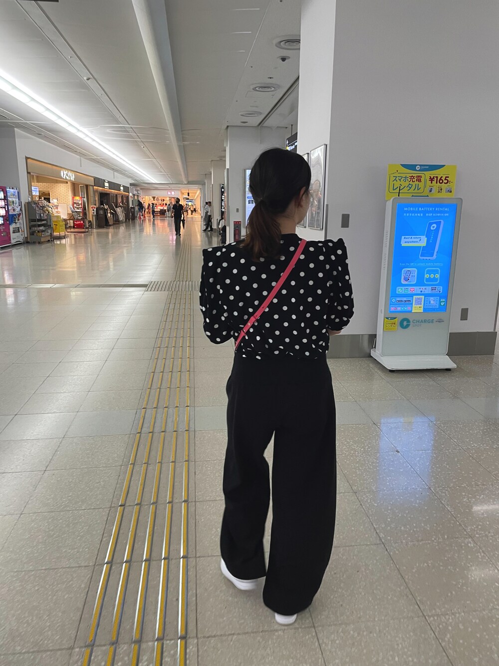 ブラック系のトップス、ブラック系のパンツ、ホワイト系のスニーカーを着用したレディースの夏コーディネートの2枚目の写真