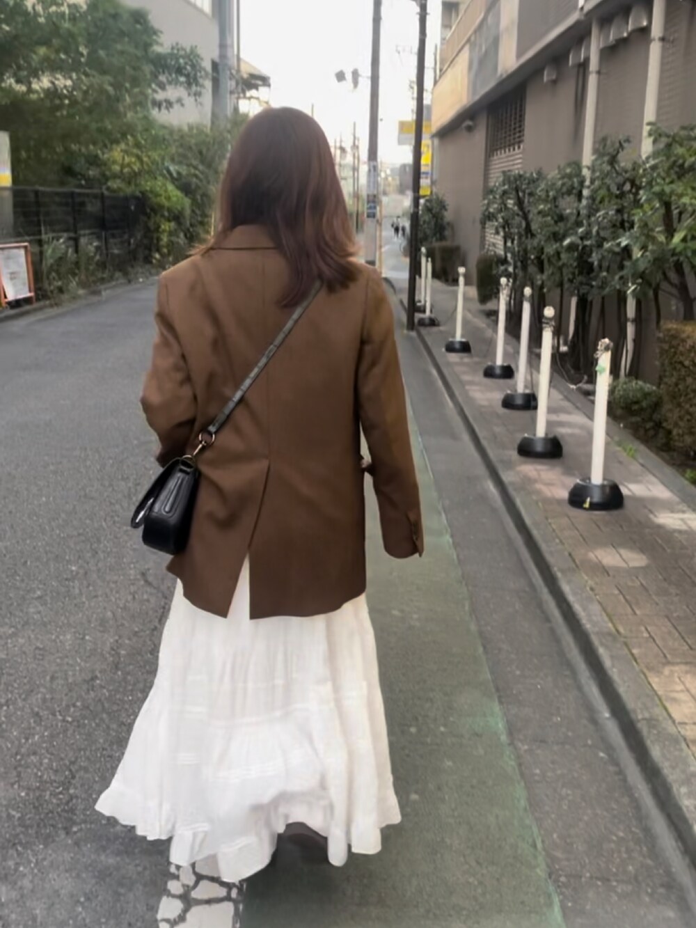 ピンク系のTシャツ/カットソー、ブラウン系のテーラードジャケット、ホワイト系のスカートを着用したレディースの秋コーディネートの3枚目の写真