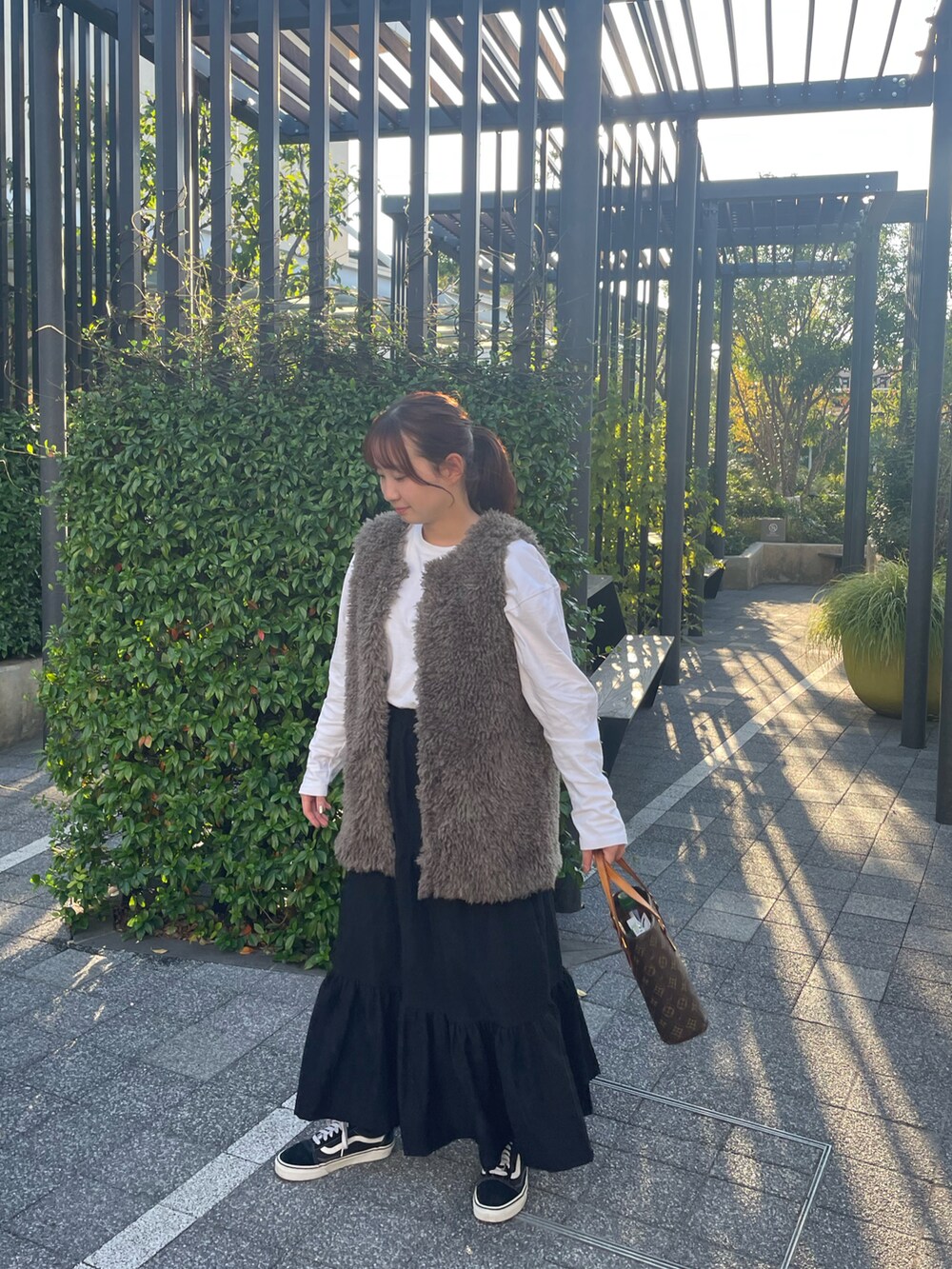 ホワイト系のTシャツ/カットソー、グレー系のベスト、ブラック系のスカートを着用したレディースの秋コーディネートの5枚目の写真