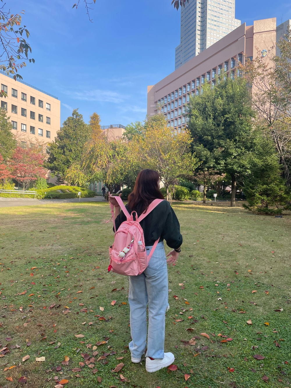 グリーン系のパーカー、ブルー系のデニムパンツ、ピンク系のバックパック/リュックを着用したレディースの秋コーディネートの3枚目の写真