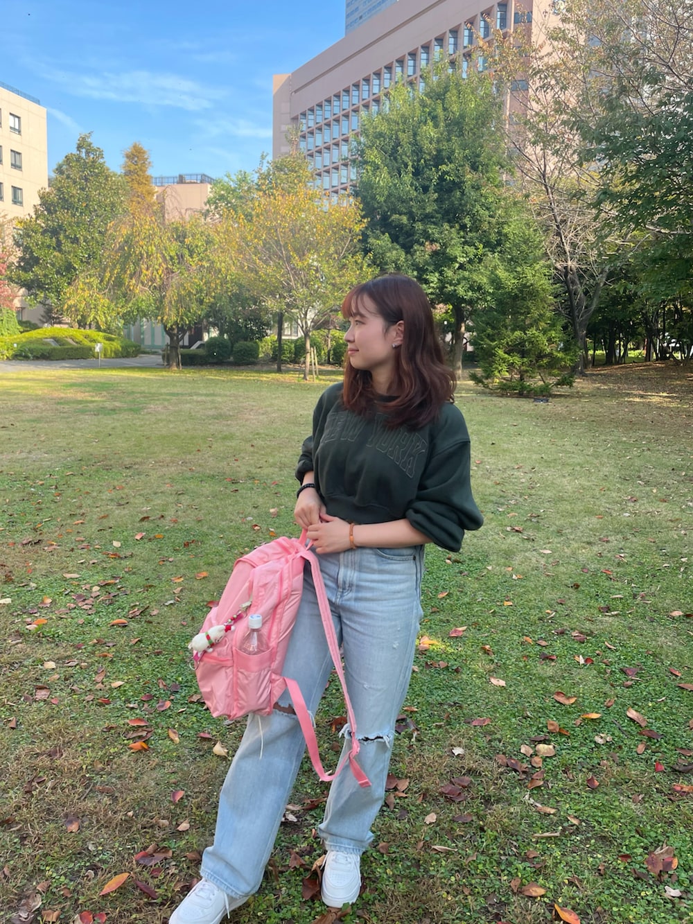 グリーン系のパーカー、ブルー系のデニムパンツ、ピンク系のバックパック/リュックを着用したレディースの秋コーディネートの2枚目の写真