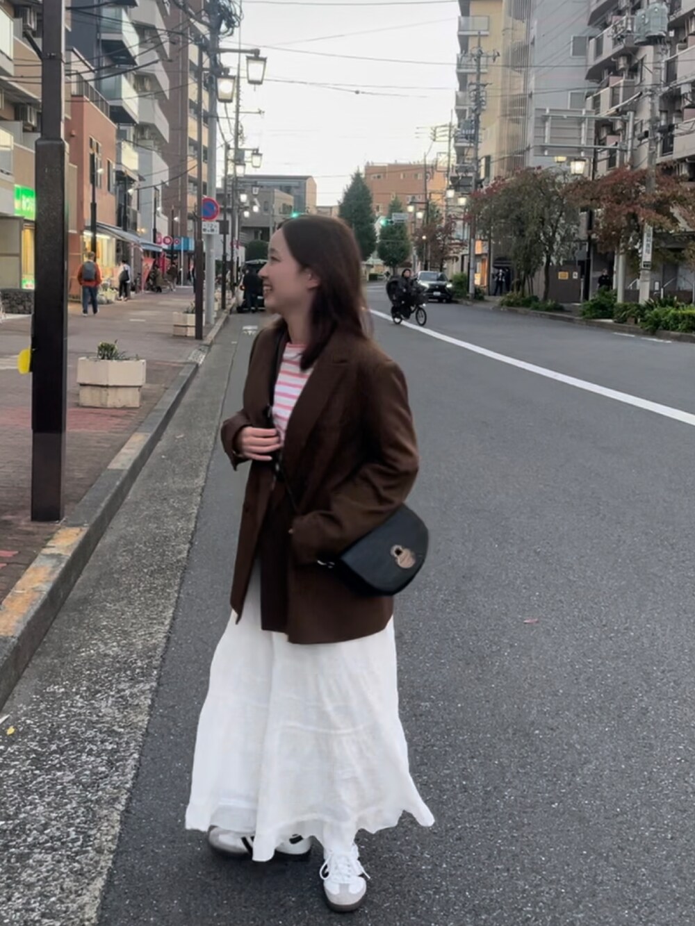 ピンク系のTシャツ/カットソー、ブラウン系のテーラードジャケット、ホワイト系のスカートを着用したレディースの秋コーディネートの2枚目の写真