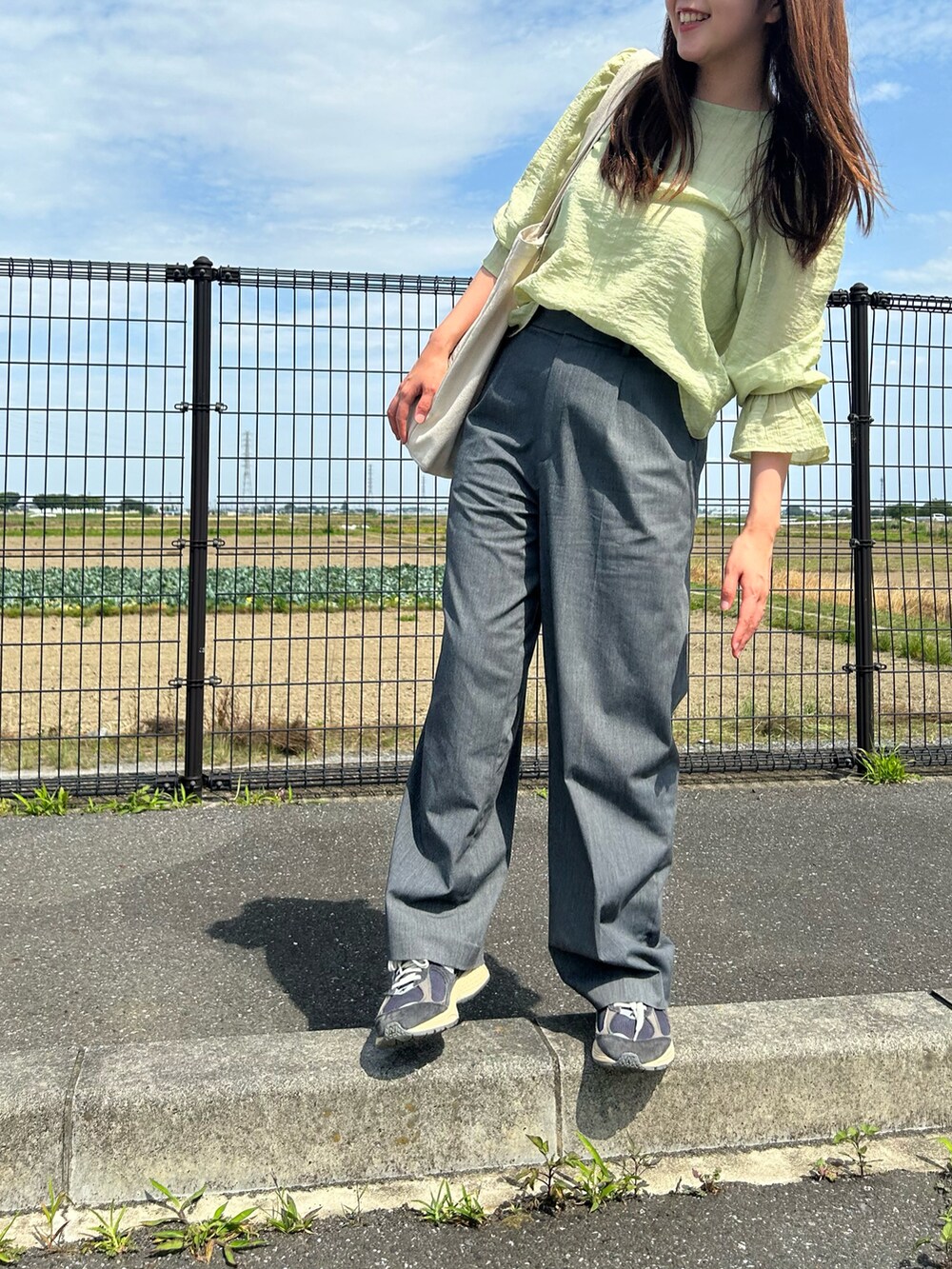 グレー系のスラックス、ブルー系のスニーカー、グリーン系のシャツ/ブラウスを着用したレディースの夏コーディネートの2枚目の写真