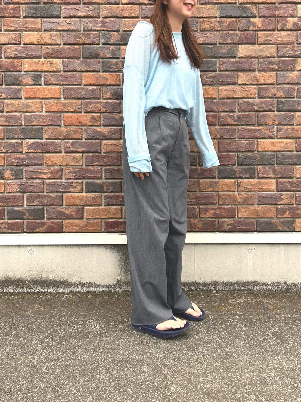ブルー系のサンダル、グレー系のスラックス、ブルー系のTシャツ/カットソーを着用したレディースの春コーディネートの2枚目の写真