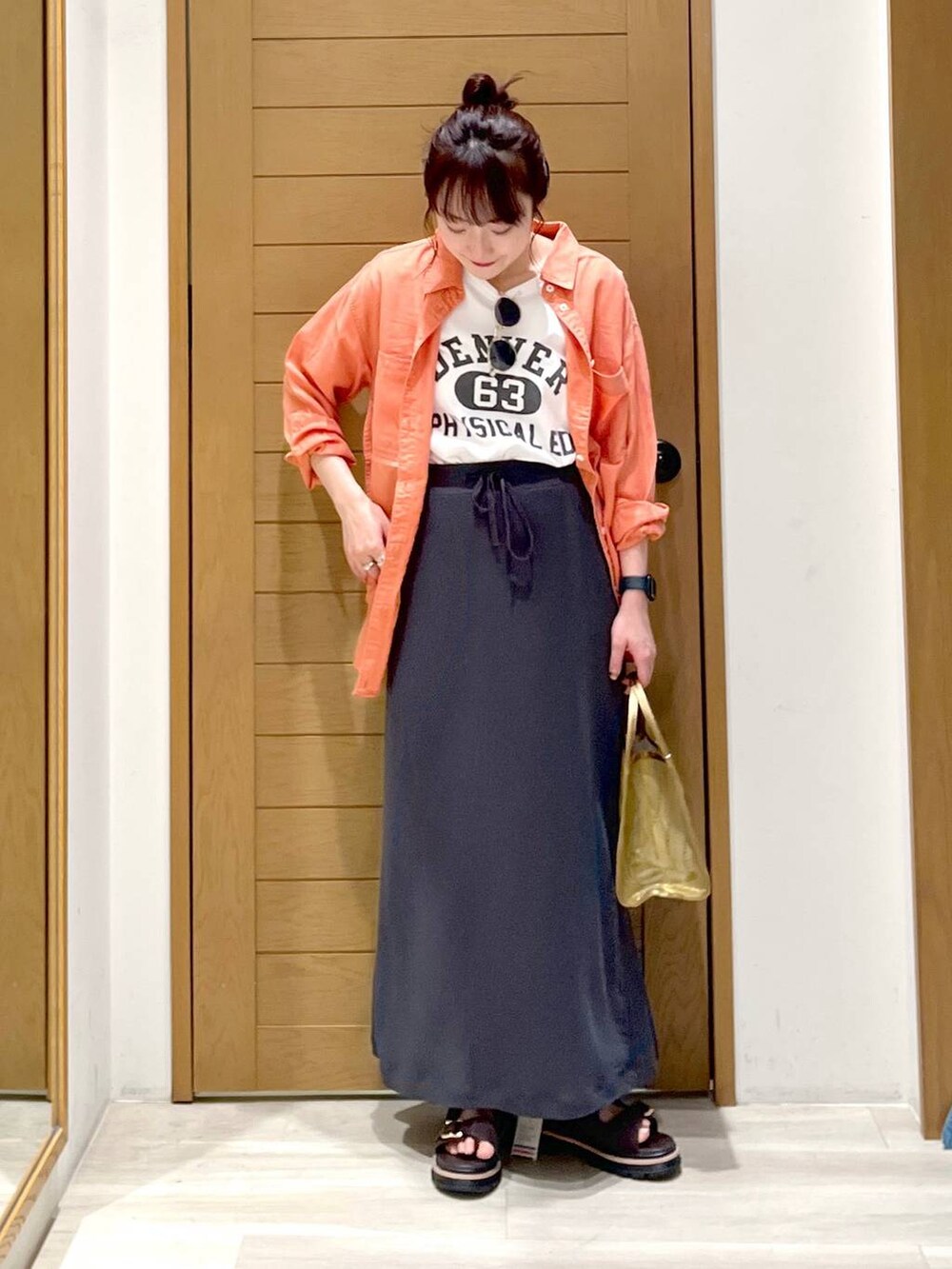 オレンジ系のシャツ/ブラウス、ブラウン系のサンダル、ホワイト系のTシャツ/カットソーを着用したレディースの春コーディネートの3枚目の写真