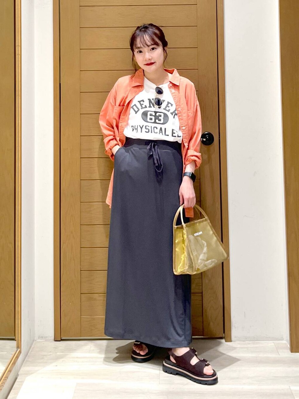 オレンジ系のシャツ/ブラウス、ブラウン系のサンダル、ホワイト系のTシャツ/カットソーを着用したレディースの春コーディネートの4枚目の写真