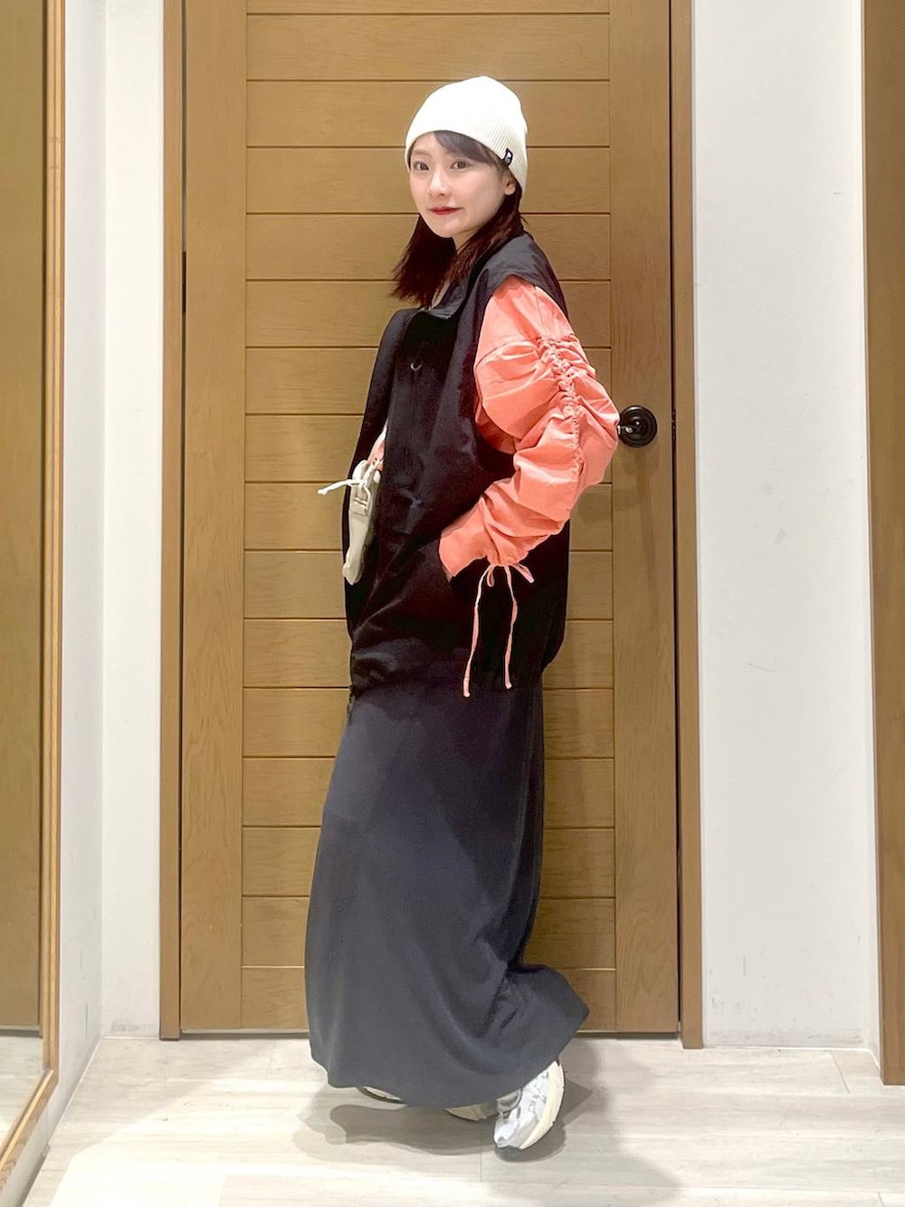 ブラック系のベスト、ベージュ系のショルダーバッグ、ピンク系のTシャツ/カットソーを着用したレディースの春コーディネートの2枚目の写真