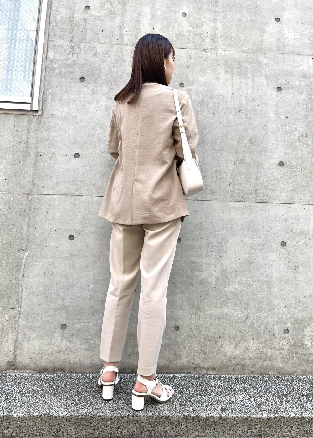 ホワイト系のショルダーバッグ、ホワイト系のTシャツ/カットソー、ベージュ系のスラックスを着用したレディースの春コーディネートの2枚目の写真