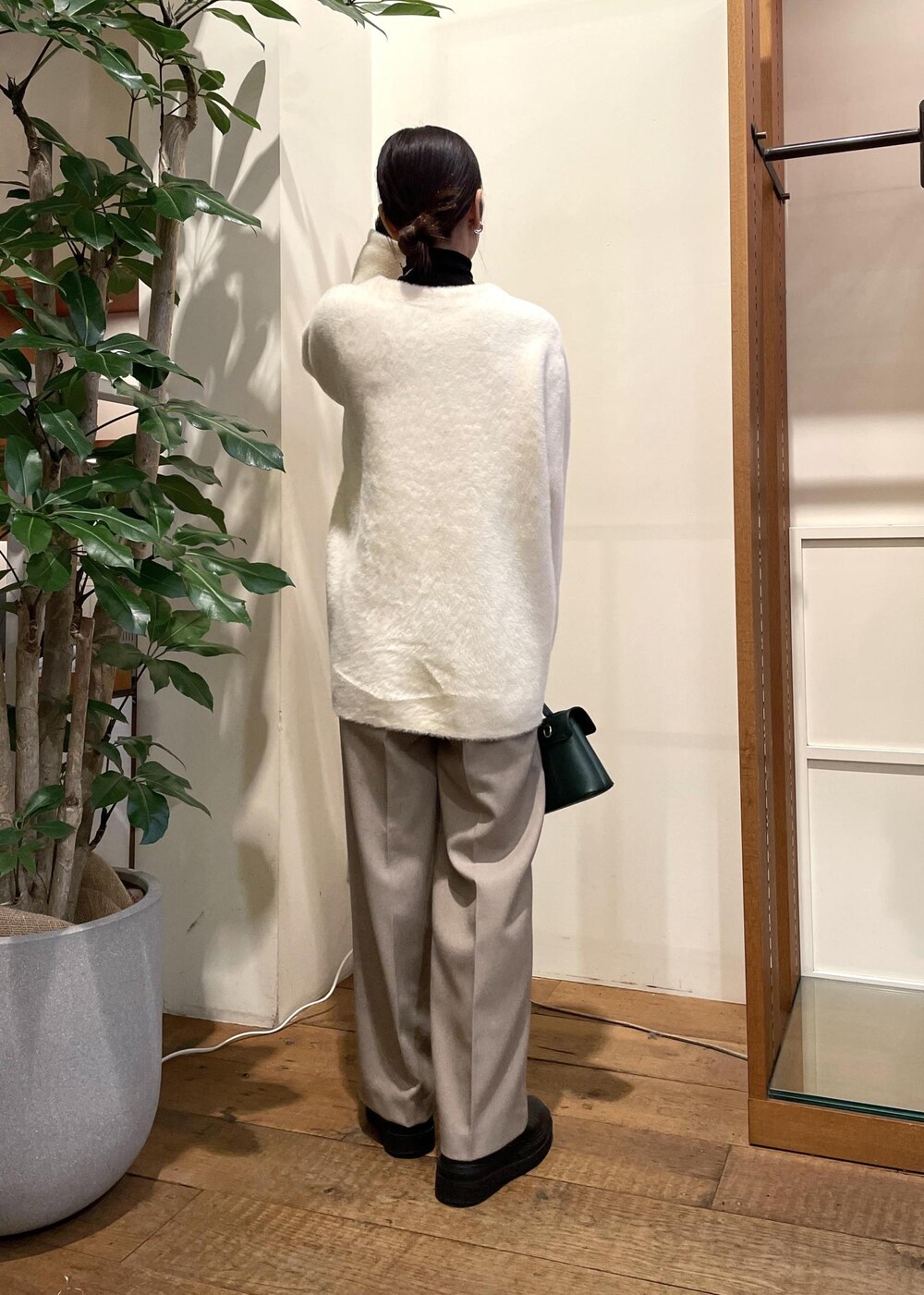 グリーン系のショルダーバッグ、ブラック系のブーツ、ブラック系のニット/セーターを着用したレディースの冬コーディネートの3枚目の写真