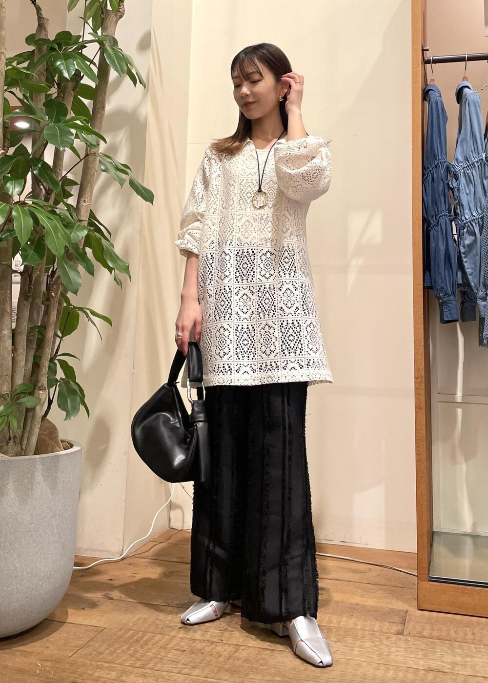 ブラック系のスラックス、ブラック系のハンドバッグ、シルバー系のサンダルを着用したレディースの春コーディネートの2枚目の写真