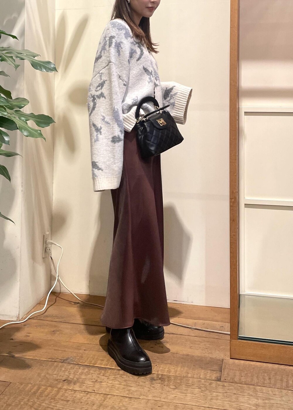 ブラック系のブーツ、グレー系のニット/セーター、ブラウン系のスカートを着用したレディースの冬コーディネートの4枚目の写真