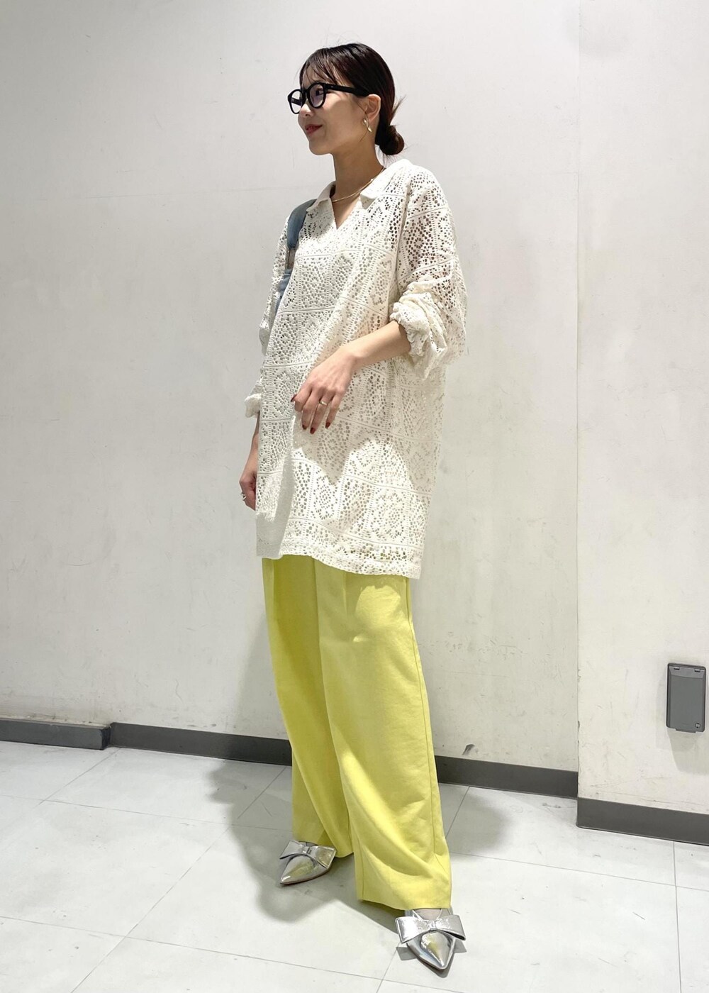 シルバー系のパンプス、イエロー系のスラックス、ブルー系のハンドバッグを着用したレディースの春コーディネートの2枚目の写真