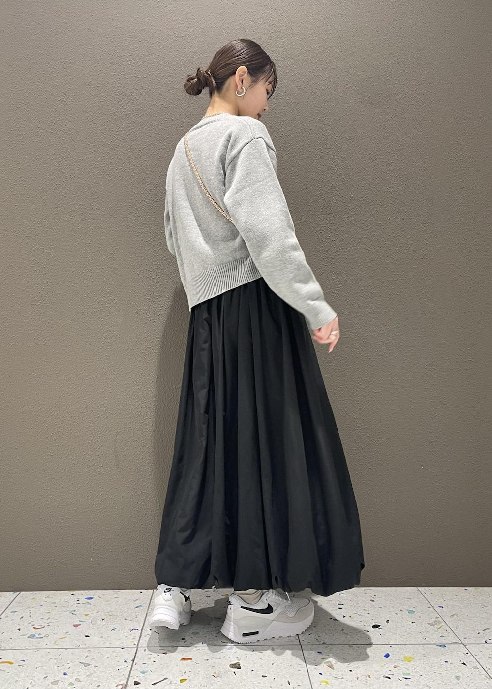 ブラック系のスカート、ピンク系のショルダーバッグ、グレー系のニット/セーターを着用したレディースの冬コーディネートの4枚目の写真