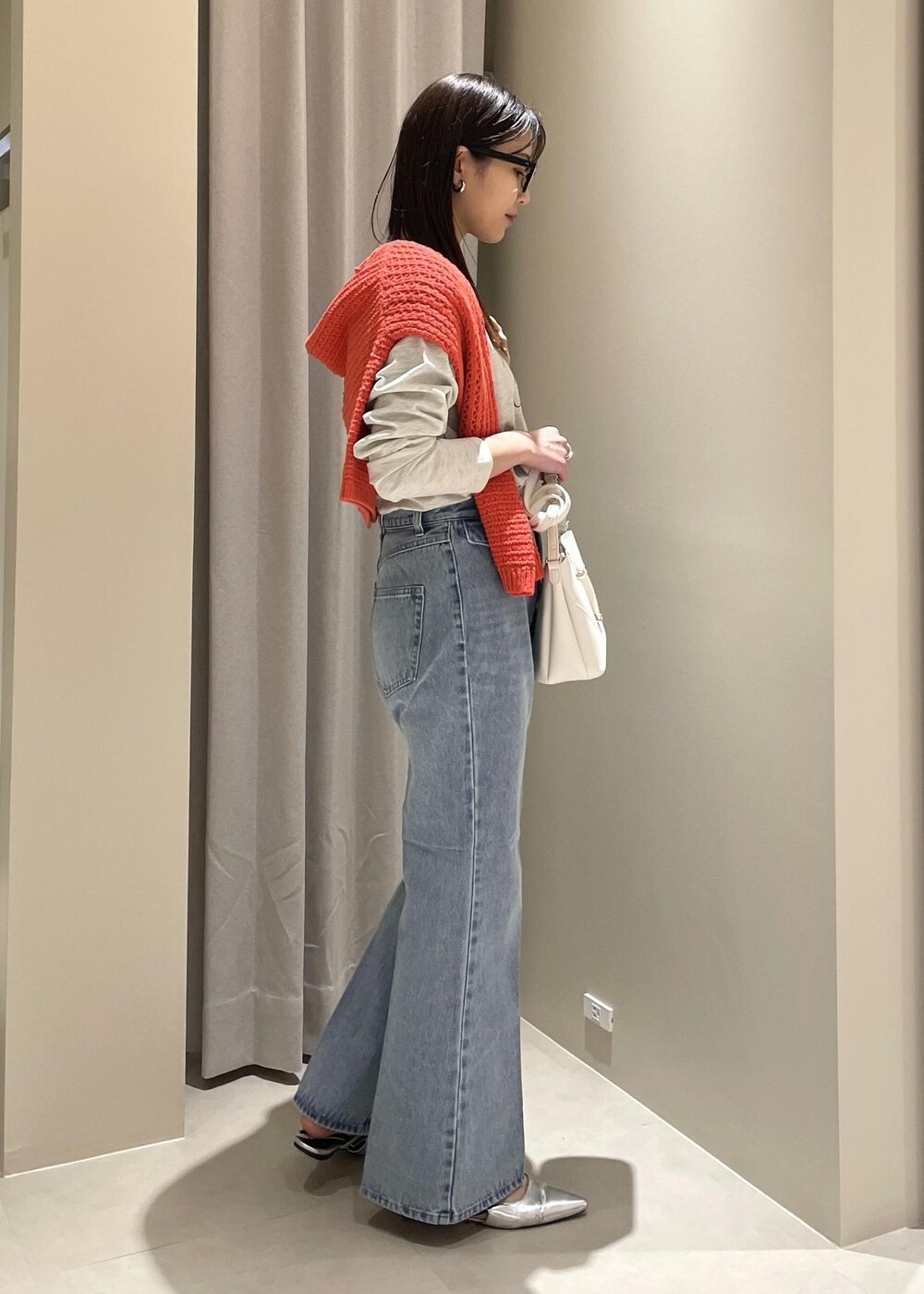 ホワイト系のショルダーバッグ、ブルー系のデニムパンツ、オレンジ系のニット/セーターを着用したレディースの春コーディネートの3枚目の写真