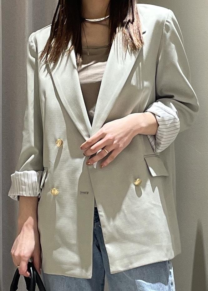 ベージュ系のキャミソール、グリーン系のテーラードジャケット、ブルー系のデニムパンツを着用したレディースの春コーディネートの6枚目の写真