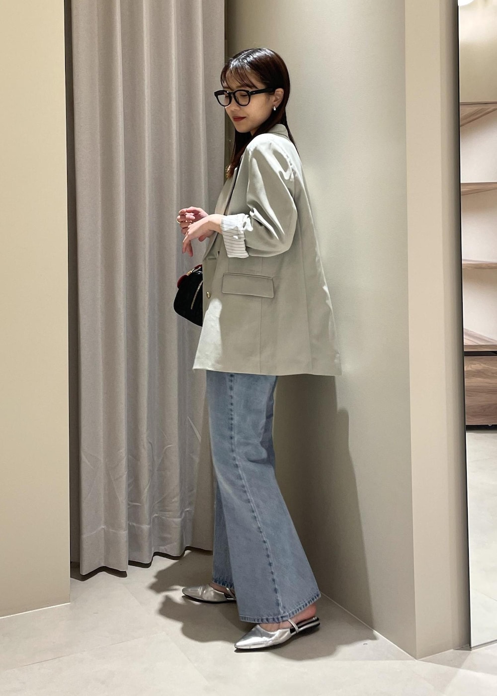 ベージュ系のキャミソール、グリーン系のテーラードジャケット、ブルー系のデニムパンツを着用したレディースの春コーディネートの3枚目の写真