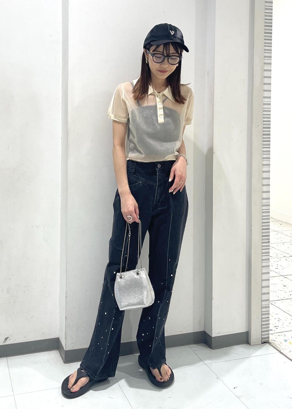 シルバー系のショルダーバッグ、ブラック系のデニムパンツ、ホワイト系のポロシャツを着用したレディースの夏コーディネートの2枚目の写真