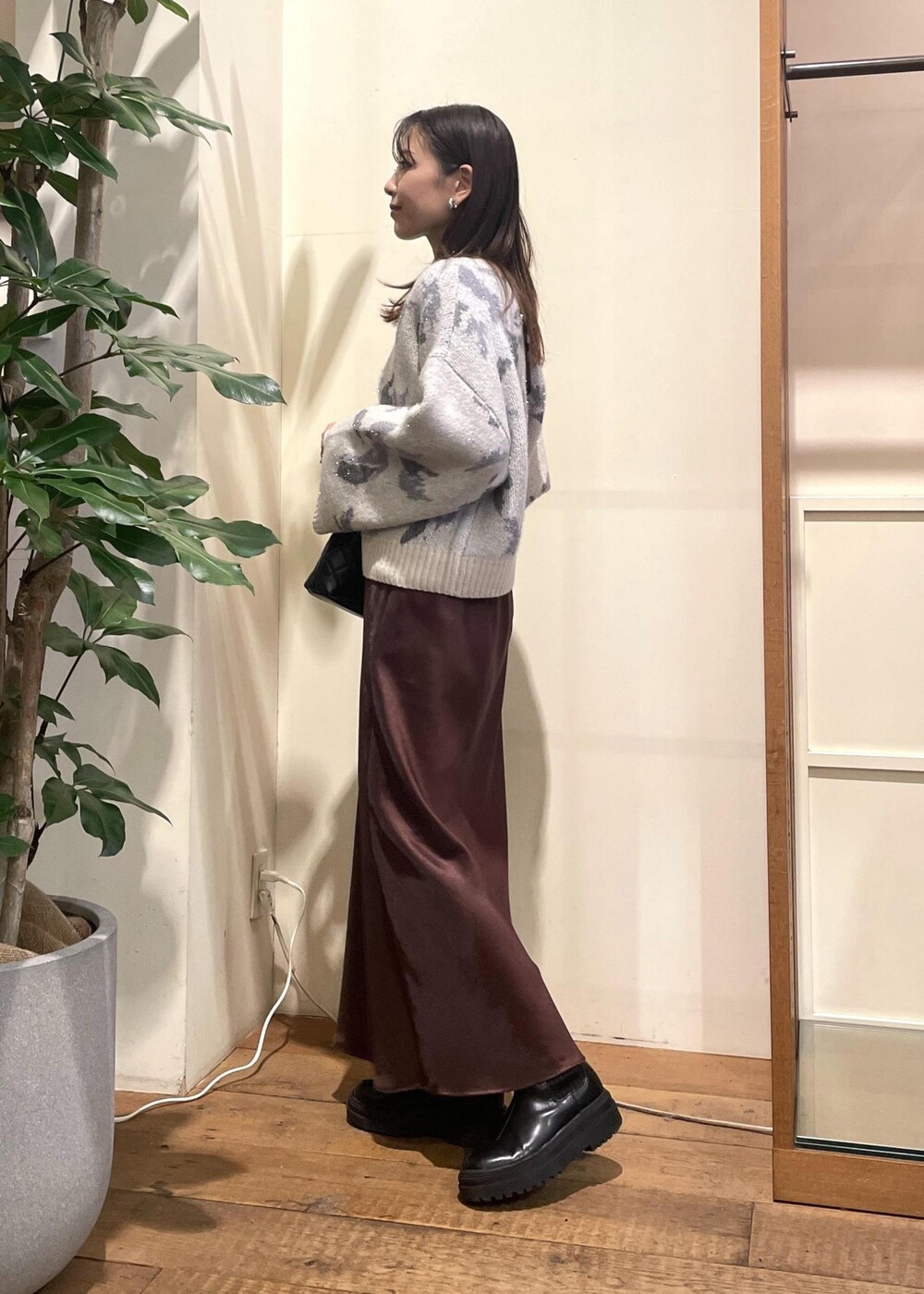 ブラック系のブーツ、グレー系のニット/セーター、ブラウン系のスカートを着用したレディースの冬コーディネートの2枚目の写真