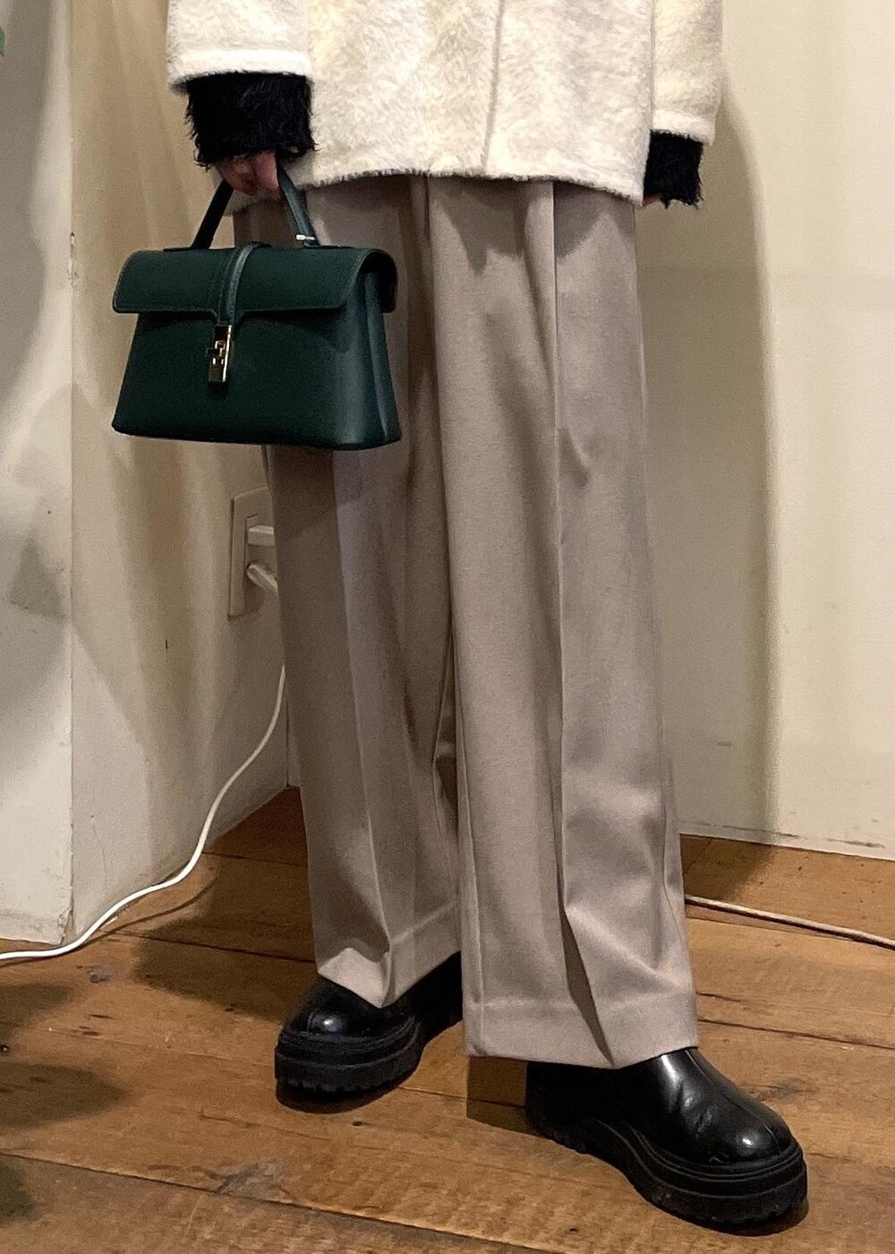 グリーン系のショルダーバッグ、ブラック系のブーツ、ブラック系のニット/セーターを着用したレディースの冬コーディネートの5枚目の写真