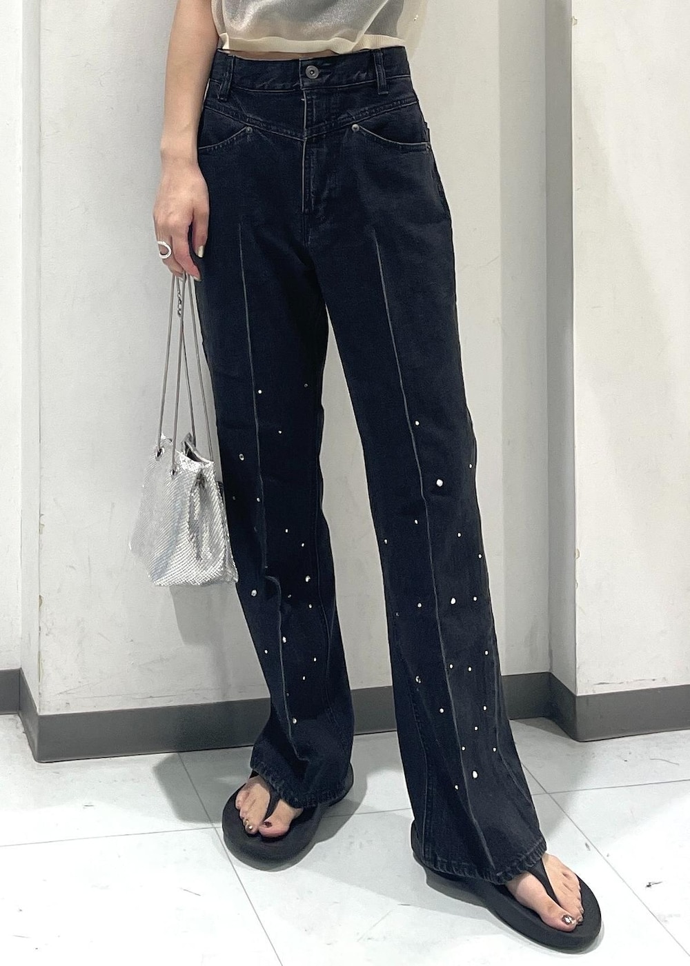 シルバー系のショルダーバッグ、ブラック系のデニムパンツ、ホワイト系のポロシャツを着用したレディースの夏コーディネートの4枚目の写真