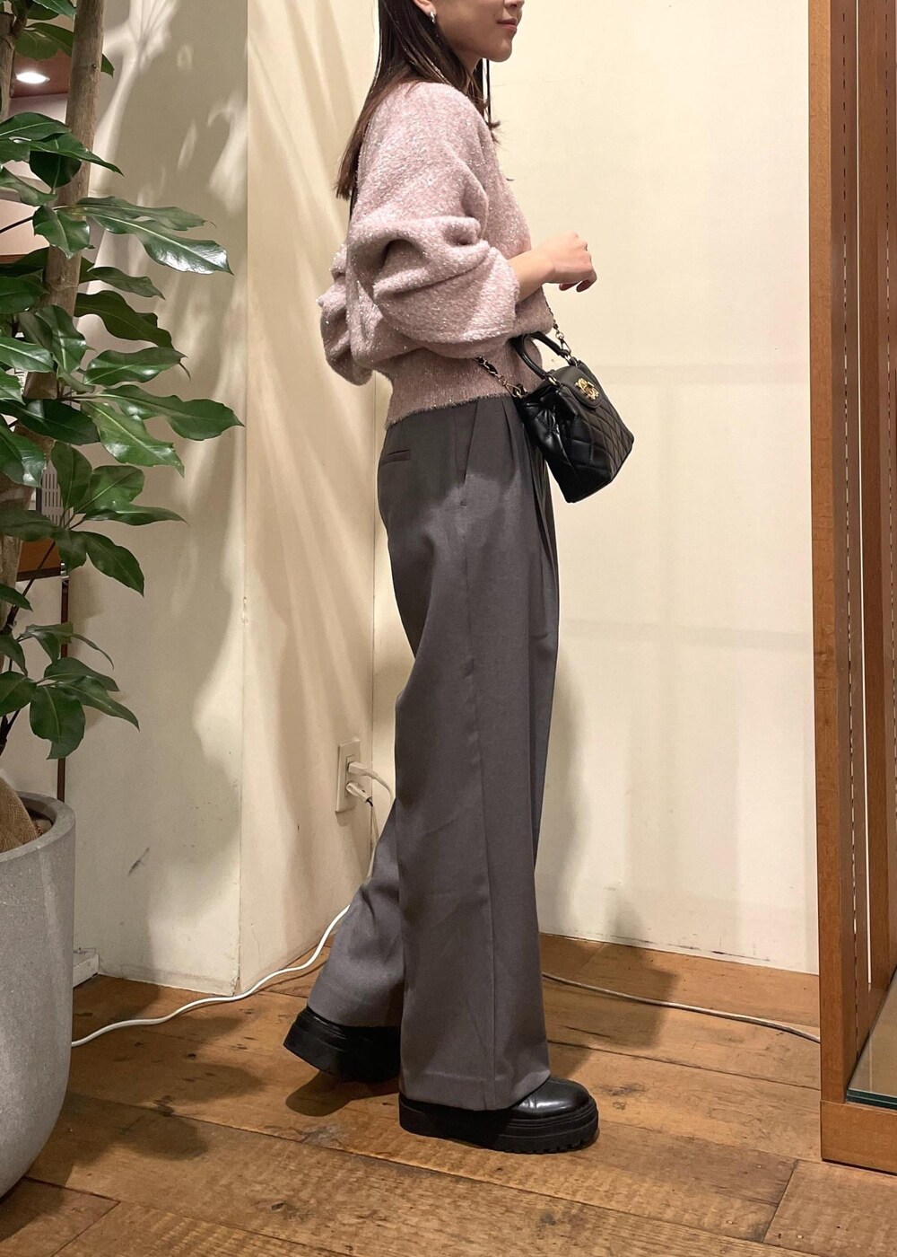 ブラック系のブーツ、グレー系のスラックス、ピンク系のニット/セーターを着用したレディースの冬コーディネートの2枚目の写真