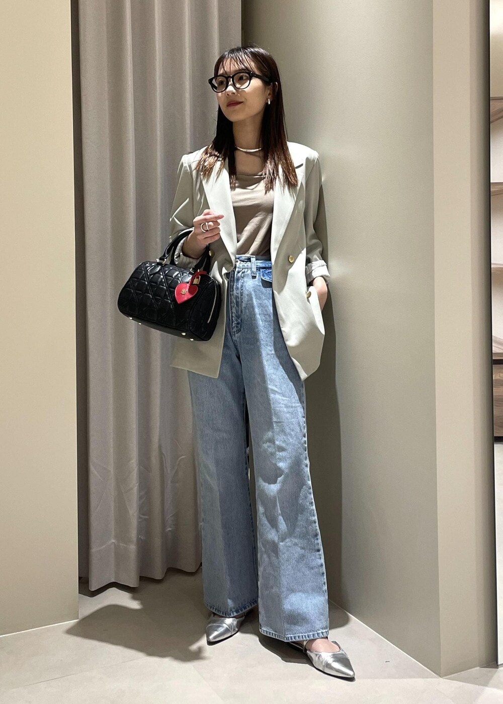 ベージュ系のキャミソール、グリーン系のテーラードジャケット、ブルー系のデニムパンツを着用したレディースの春コーディネートの2枚目の写真