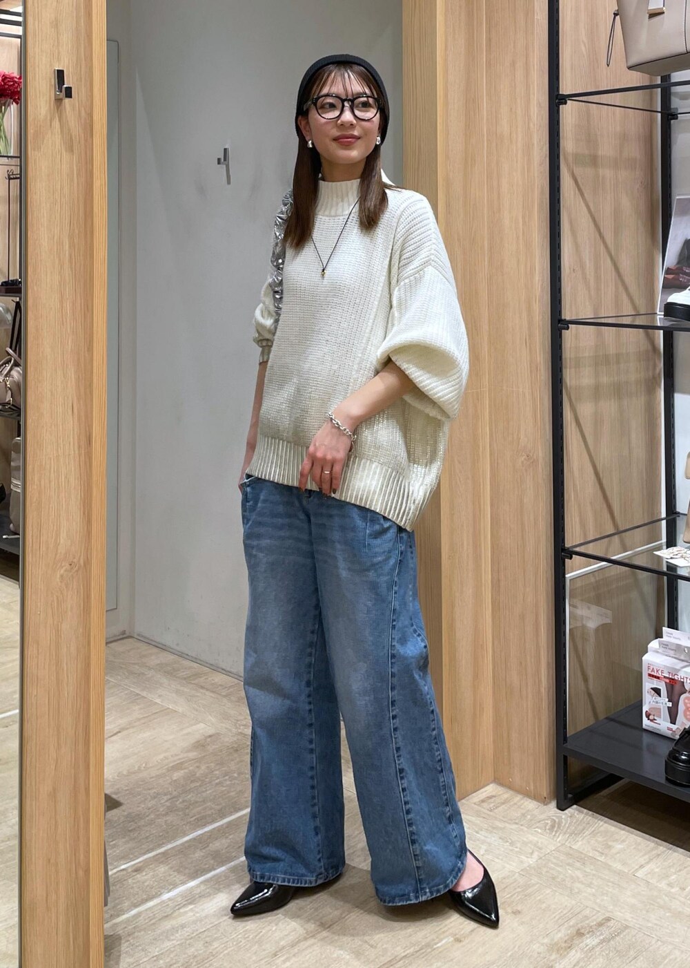 ホワイト系のニット/セーター、ブルー系のデニムパンツ、ブラック系のパンプスを着用したレディースの冬コーディネートの2枚目の写真
