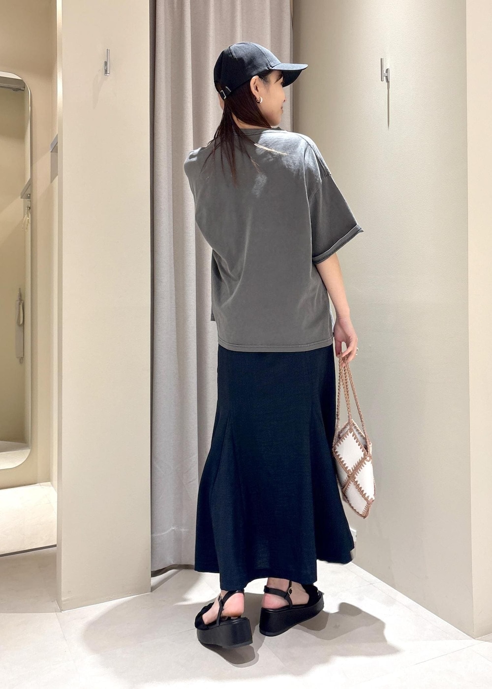 ホワイト系のハンドバッグ、ブルー系のスカート、グレー系のTシャツ/カットソーを着用したレディースの春コーディネートの3枚目の写真