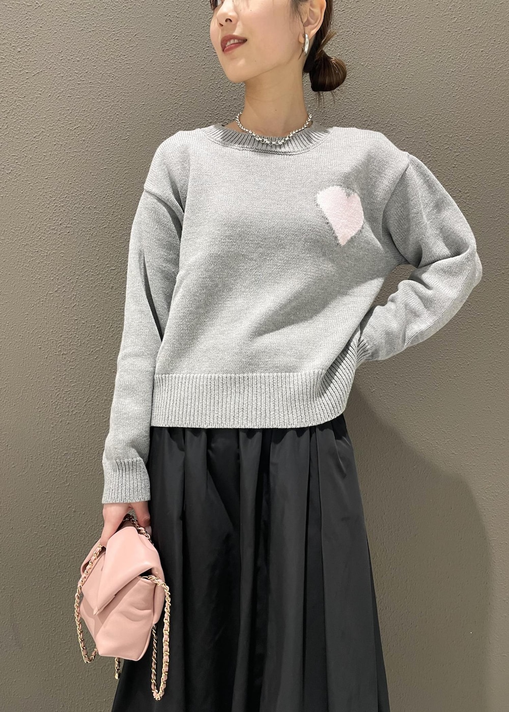 ブラック系のスカート、ピンク系のショルダーバッグ、グレー系のニット/セーターを着用したレディースの冬コーディネートの5枚目の写真