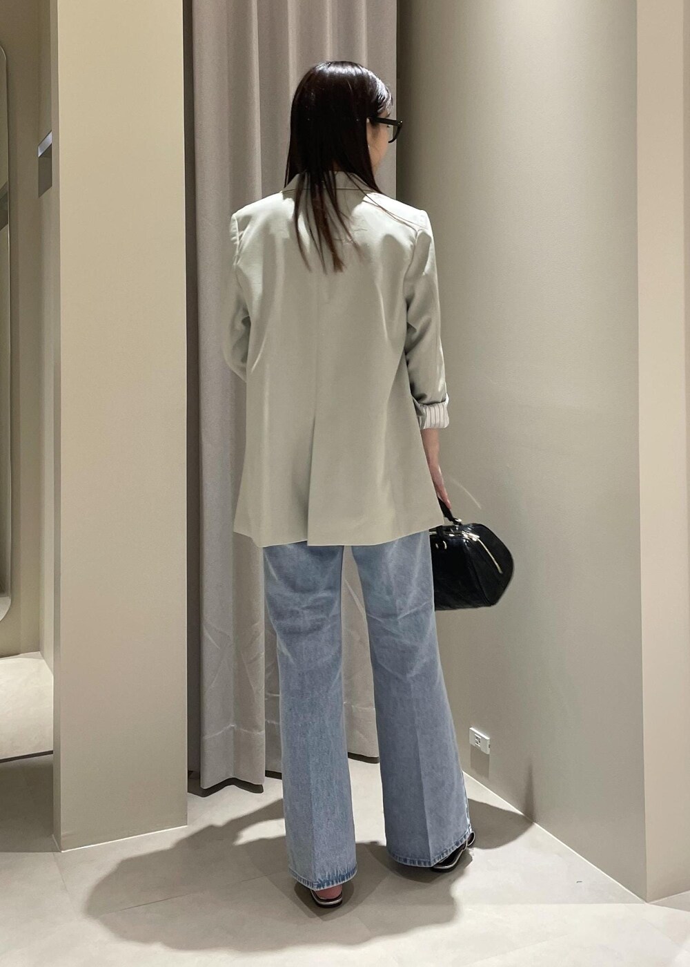 ベージュ系のキャミソール、グリーン系のテーラードジャケット、ブルー系のデニムパンツを着用したレディースの春コーディネートの5枚目の写真