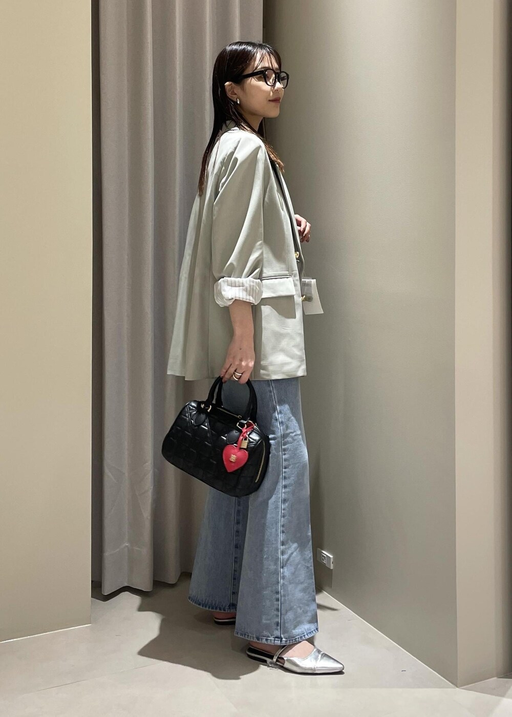 ベージュ系のキャミソール、グリーン系のテーラードジャケット、ブルー系のデニムパンツを着用したレディースの春コーディネートの4枚目の写真