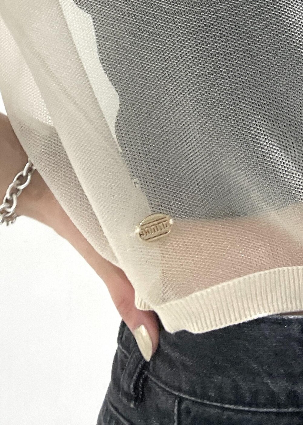 シルバー系のショルダーバッグ、ブラック系のデニムパンツ、ホワイト系のポロシャツを着用したレディースの夏コーディネートの7枚目の写真