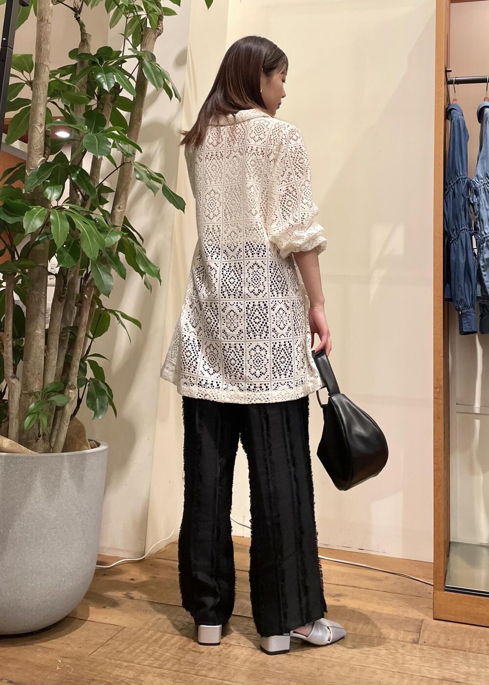 ブラック系のスラックス、ブラック系のハンドバッグ、シルバー系のサンダルを着用したレディースの春コーディネートの4枚目の写真