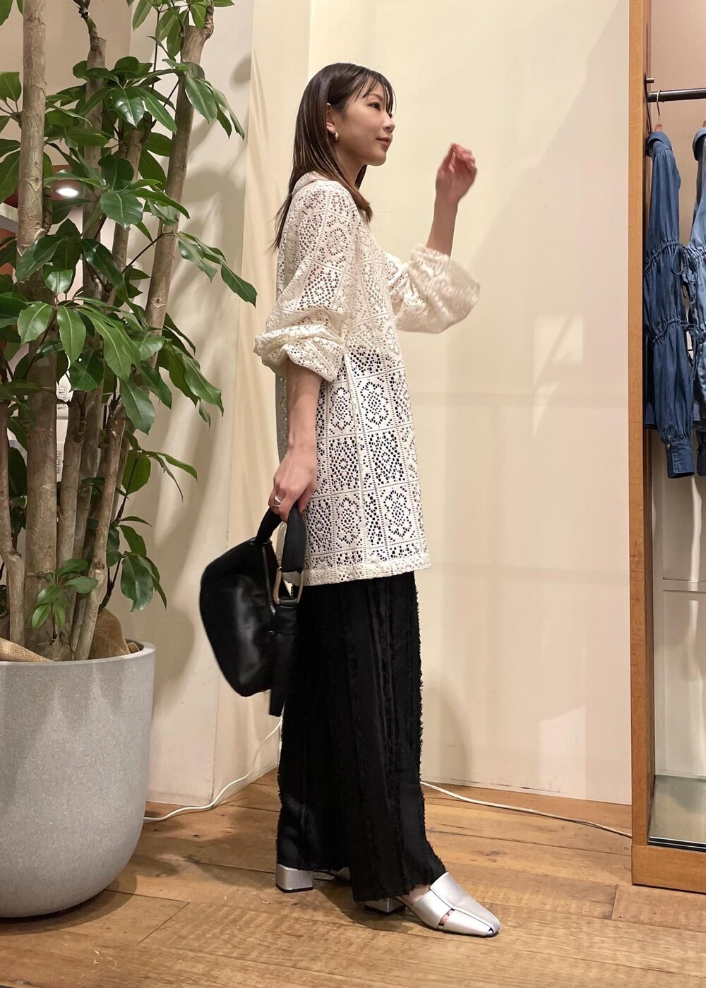 ブラック系のスラックス、ブラック系のハンドバッグ、シルバー系のサンダルを着用したレディースの春コーディネートの3枚目の写真