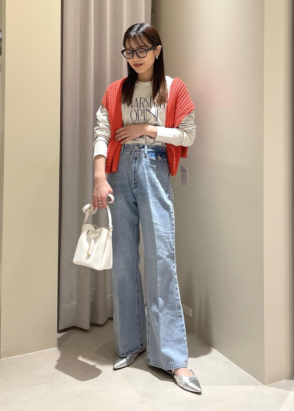 ホワイト系のショルダーバッグ、ブルー系のデニムパンツ、オレンジ系のニット/セーターを着用したレディースの春コーディネートの2枚目の写真
