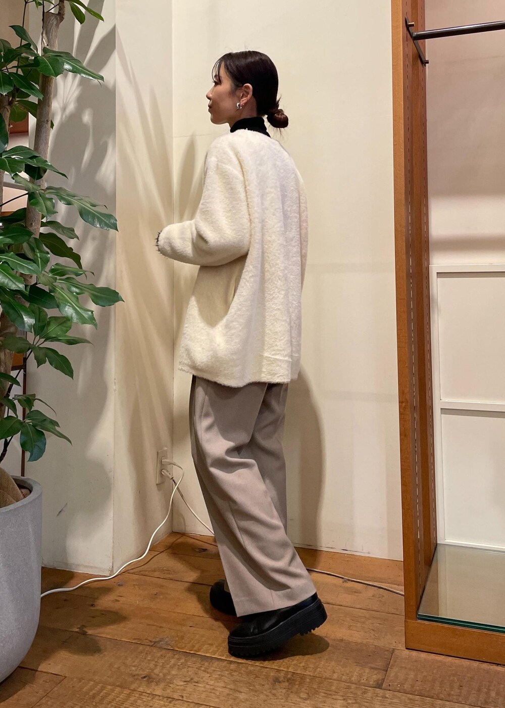 グリーン系のショルダーバッグ、ブラック系のブーツ、ブラック系のニット/セーターを着用したレディースの冬コーディネートの2枚目の写真