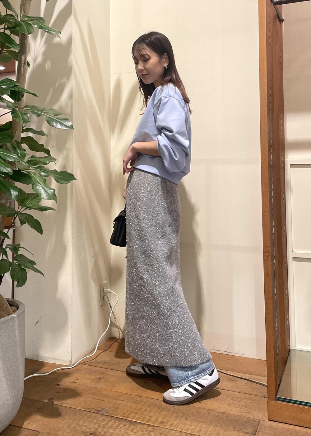 グレー系のスカート、ブルー系のデニムパンツ、ブラック系のショルダーバッグを着用したレディースの冬コーディネートの2枚目の写真