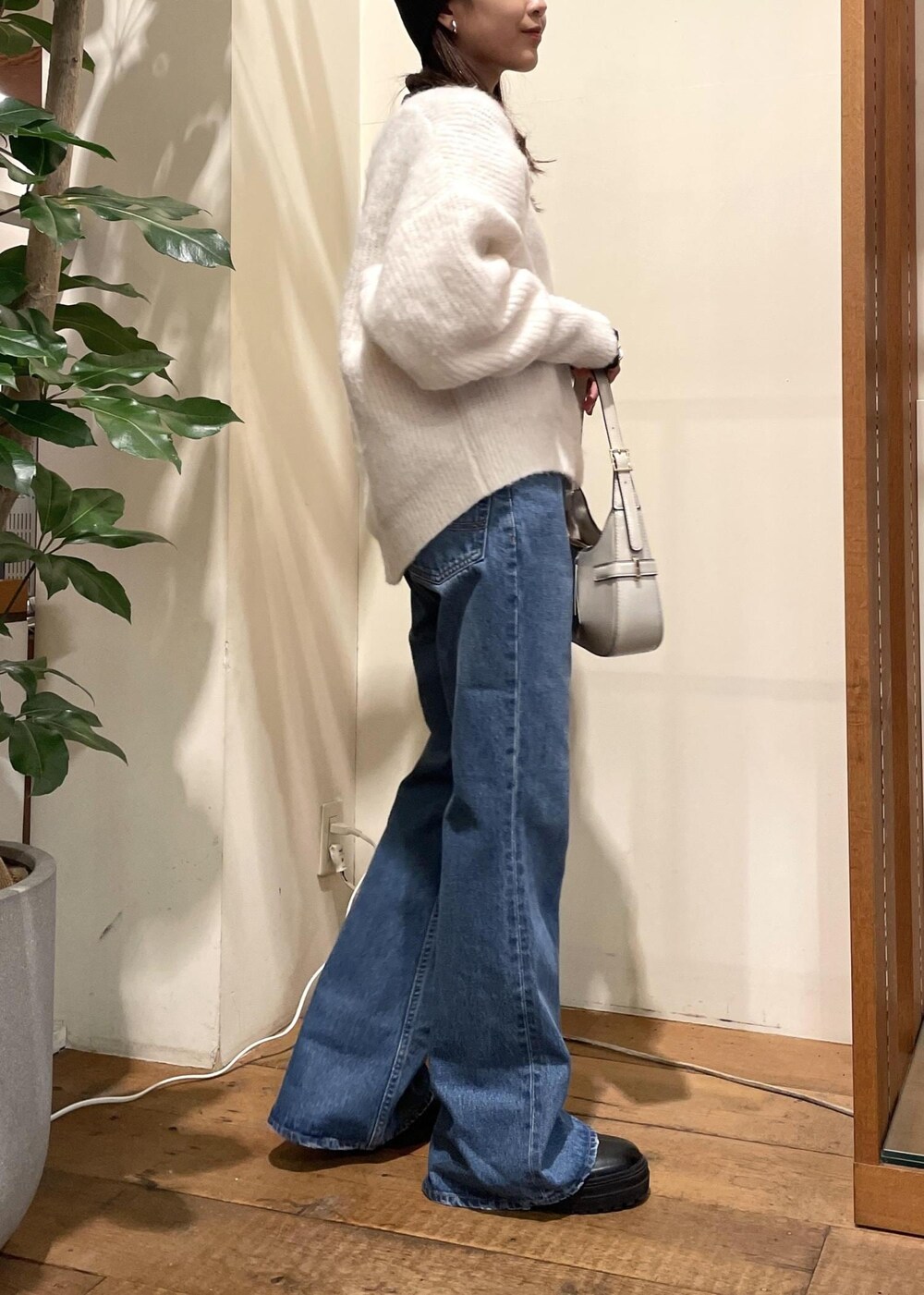 ブルー系のデニムパンツ、ブラック系のブーツ、ホワイト系のハンドバッグを着用したレディースの冬コーディネートの2枚目の写真